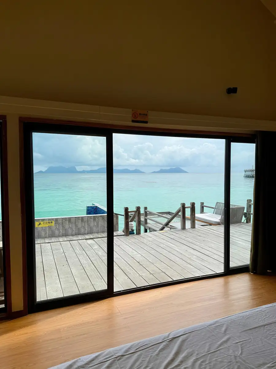 A cozy bedroom at Jelly Sea Resort near Bum Bum Island detailing a bed with towel art facing glass doors to the private balcony, authentic wooden floors with glossy hardwood, and air con.
