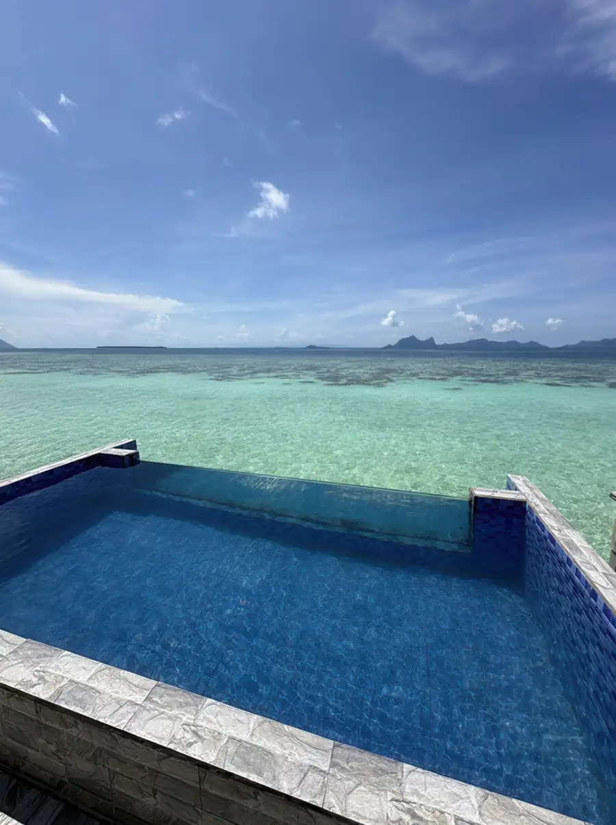 Crystal-clear water in a private glass-sided pool at Jelly Sea Resort. A romantic over the water escape near Semporna offering uninterrupted views of Pulau Bohey Dulang at the horizon.