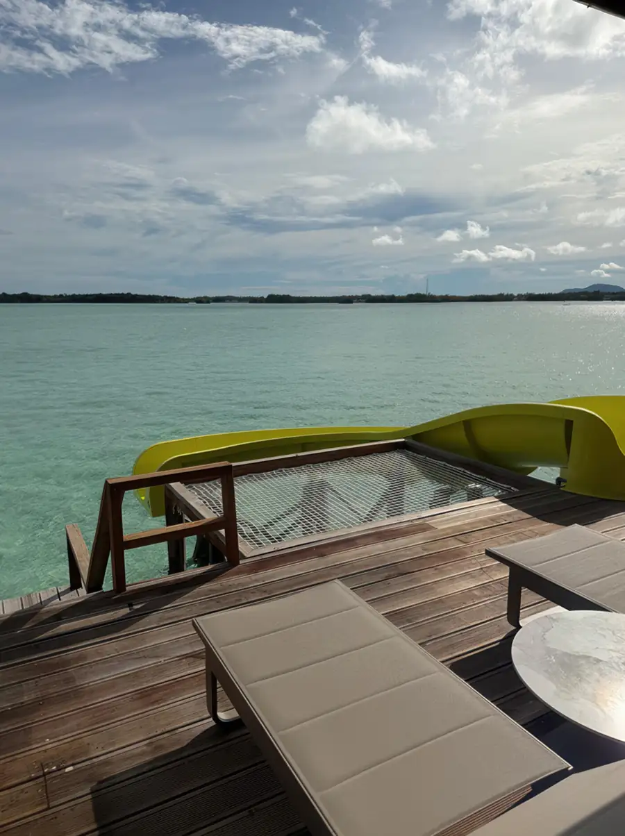 Close-up view of direct wooden access stairs plunging into vibrant, crystal-clear water at Jelly Sea Resort. A barefoot luxury retreat offering immediate snorkelling in the Celebes Sea.