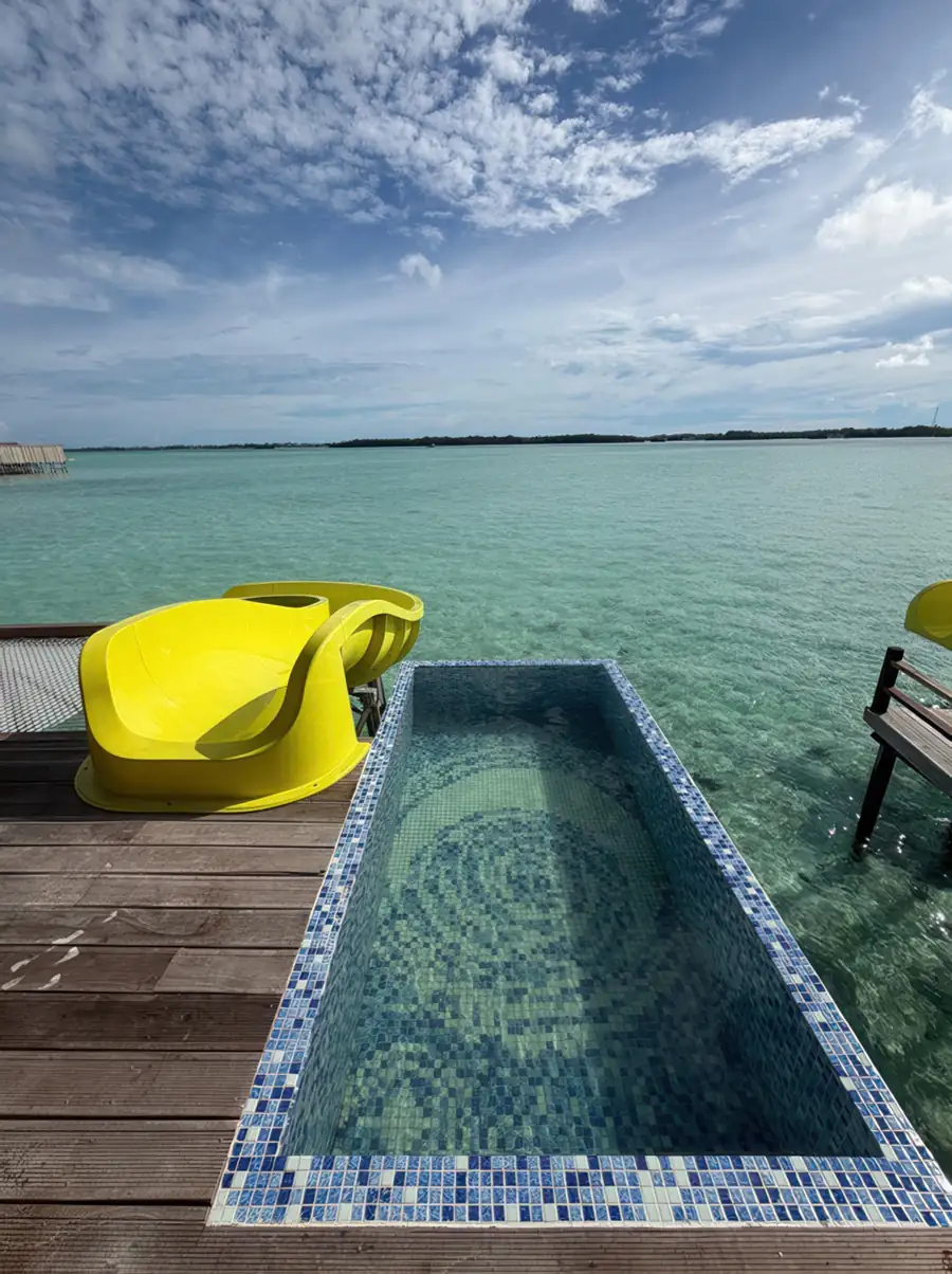 Private sun-soaked balcony featuring a glass plunge pool, an overwater slide and a suspended mesh bed at Jelly Sea Resort. The perfect Semporna water resort for watching the sea turtles glide by.