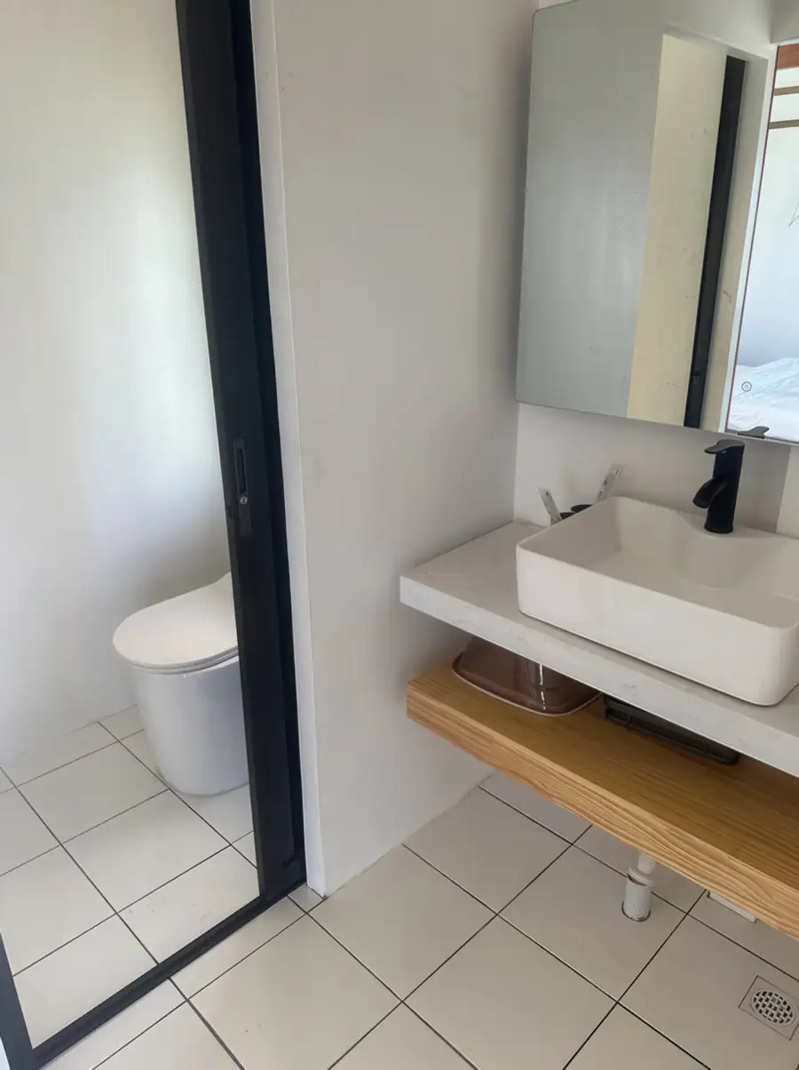 A pristine bathroom wet area at Jelly Sea Resort presenting a glass shower enclosure, modern light grey wall tiles, and a high-quality electric shower system.