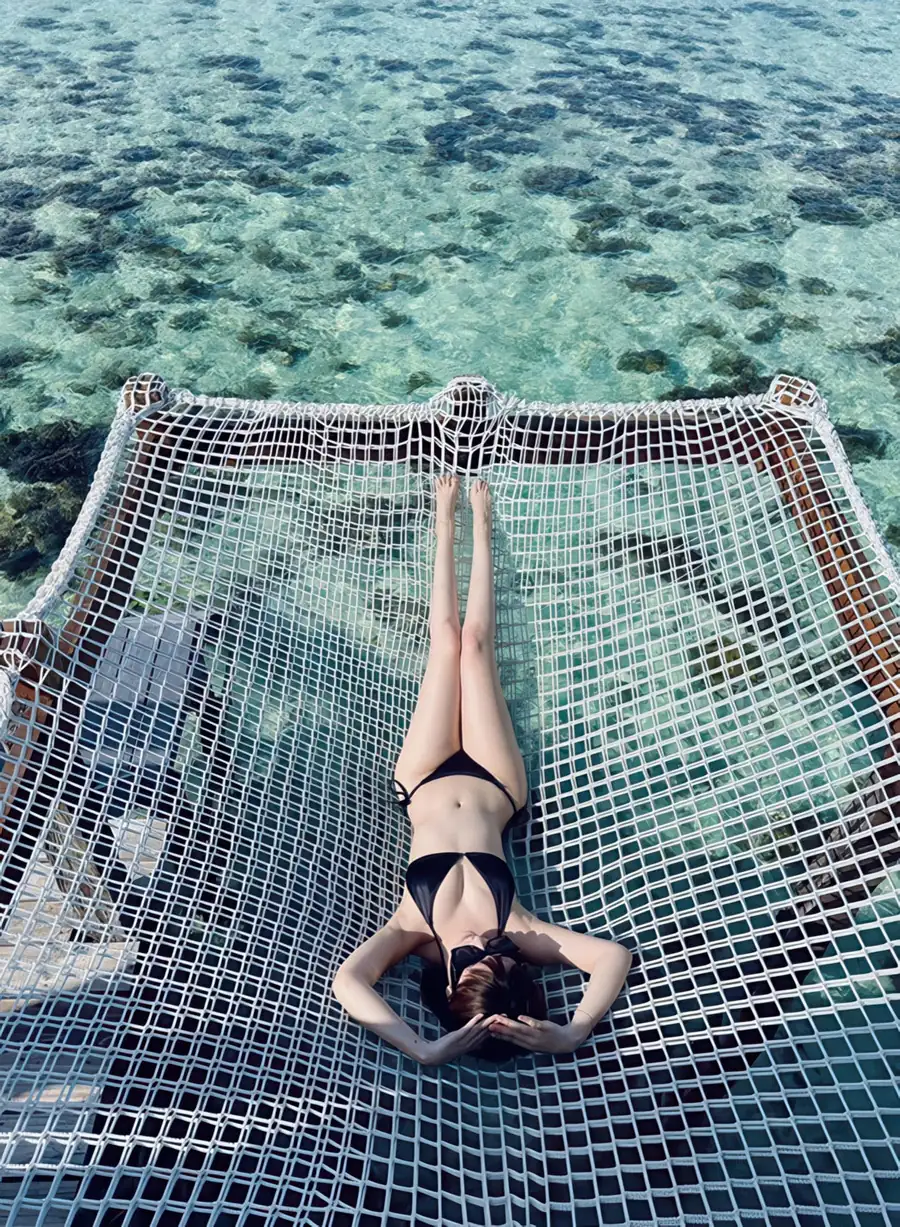 Guest enjoying a catamaran-style net lounge at Jelly Sea Resort. A beautiful floating paradise perfectly designed for a midday rest above the turquoise Celebes Sea.
