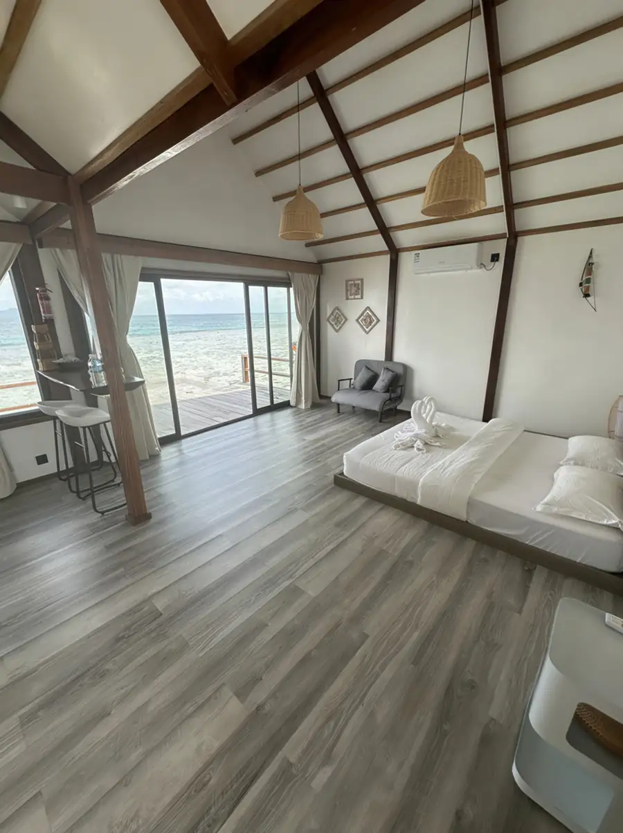 A serene bedroom at Jelly Sea Resort near Semporna featuring a large bed facing glass doors opening onto the balcony with seaviews and aircon for comfort.
