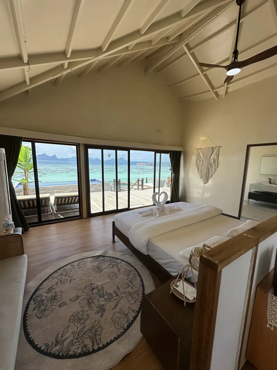 A grand bedroom at Jelly Sea Resort in the Celebes Sea where the king bed faces panoramic glass doors opening onto the private balcony with seaviews and pool, cooled by air conditioning.