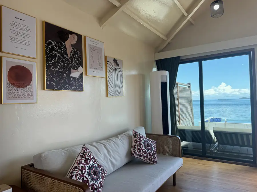 A chic room at Jelly Sea Resort near the Tun Sakaran Marine Park featuring a modern sofa with patterned pillows, gallery wall art, and authentic wooden floors, including a/c.