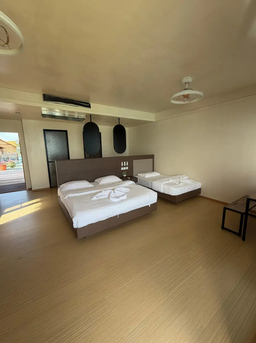A large family room at Jelly Sea Resort in the Celebes Sea featuring one king and one single bed, modern style decor, and authentic wooden floors with glossy hardwood floors, with aircon.
