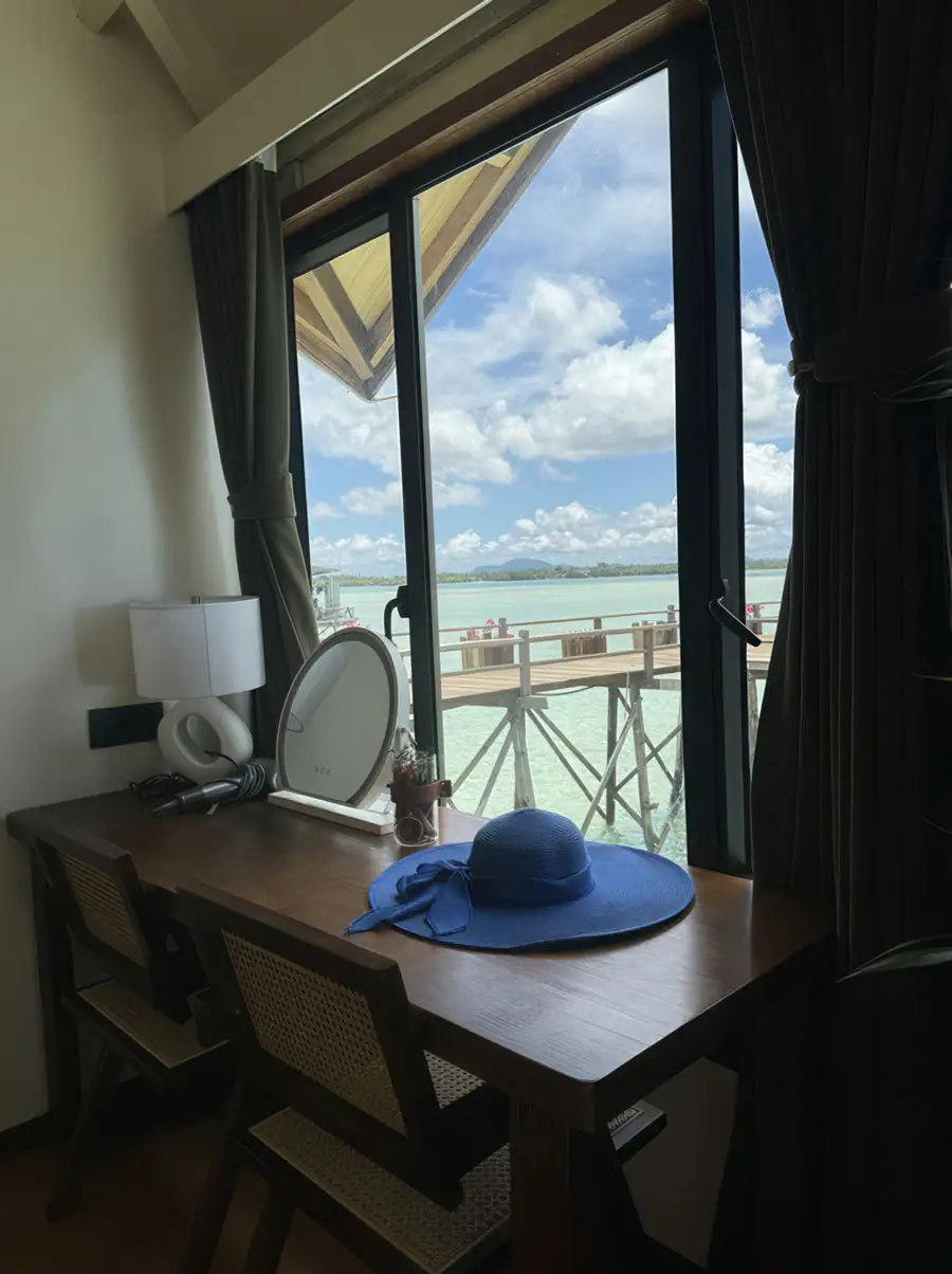 A bright room at Jelly Sea Resort near the Tun Sakaran Marine Park featuring a wooden desk by the window with ocean views, authentic wooden floors, and aircon for focus.