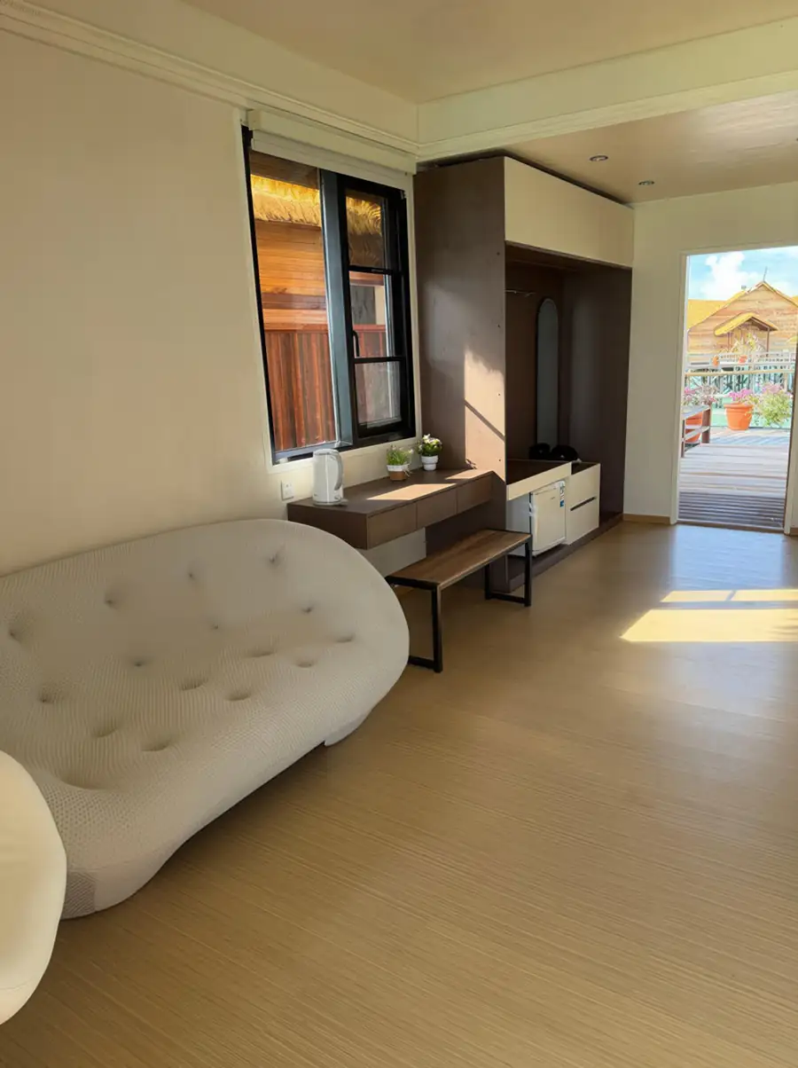 A bright bedroom at Jelly Sea Resort near Bum Bum Island featuring a tufted sofa and direct access to the private balcony via glass doors, smooth wooden boards, and air con.