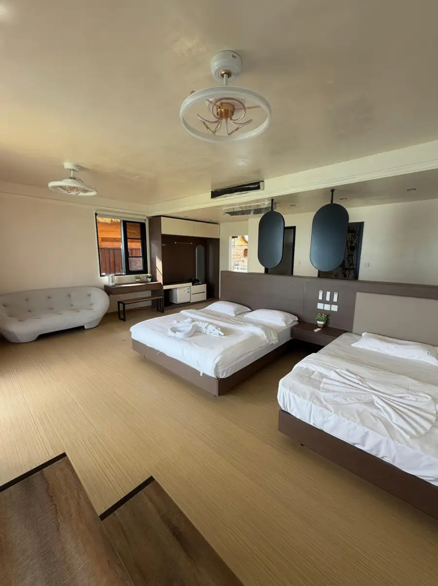 A contemporary bedroom at Jelly Sea Resort near Semporna with a large bed and single bed, modern urban furniture, smooth wooden boards, and air conditioning.