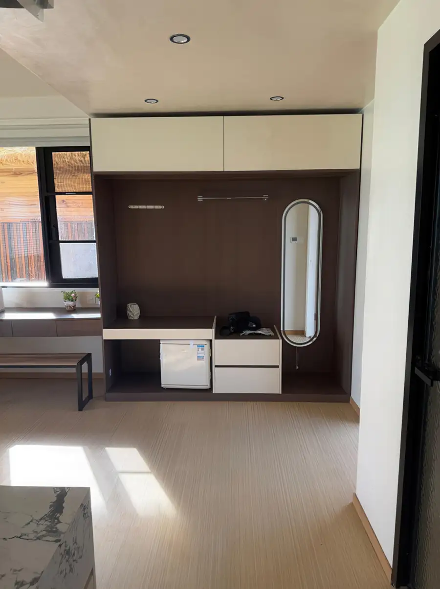 A modern bedroom at Jelly Sea Resort near Bum Bum Island showcasing a sleek open wardrobe with a mini fridge and smooth wooden boards, air conditioning.