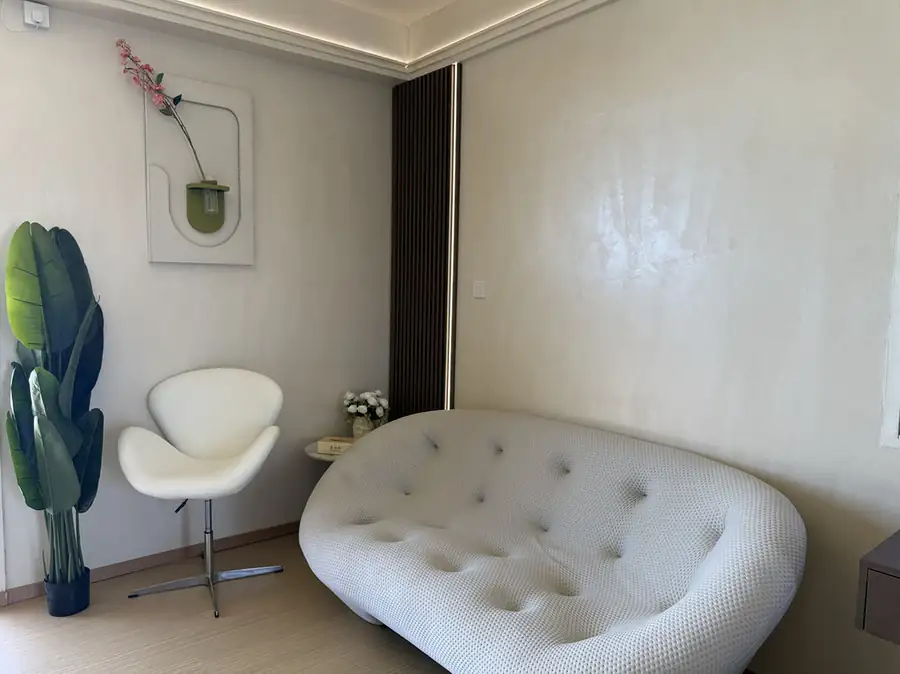 A contemporary bedroom at Jelly Sea Resort near Semporna with a tufted white sofa and modern style decor over smooth wooden boards, air con.