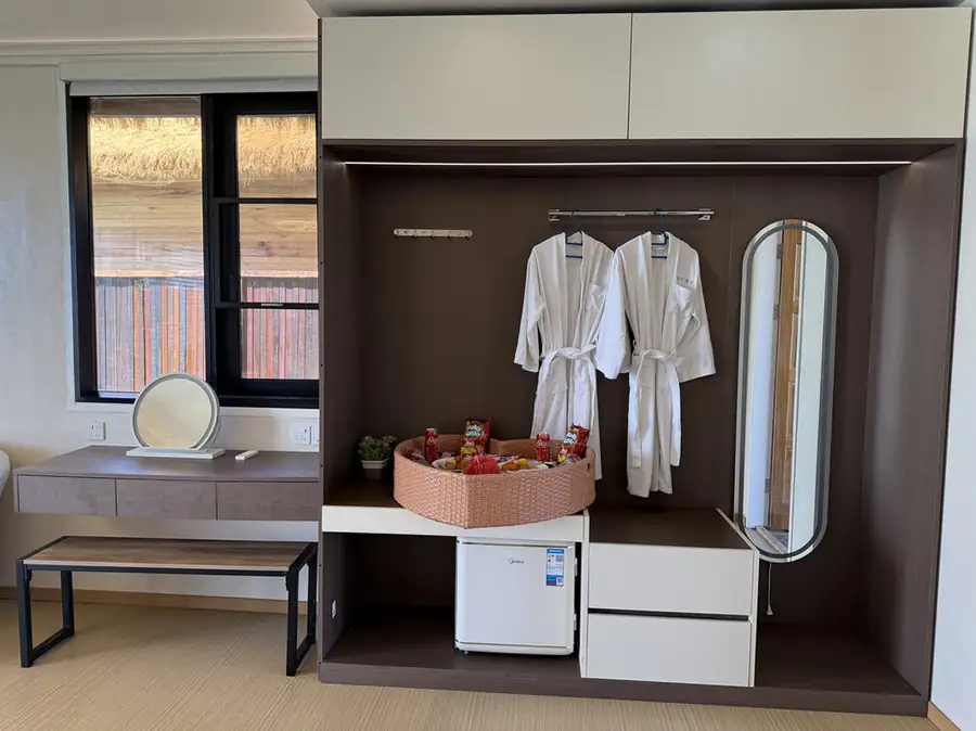 A modern bedroom at Jelly Sea Resort near Bum Bum Island featuring a stylish vanity, a mini fridge, bathrobes, and smooth wooden boards, air conditioning.