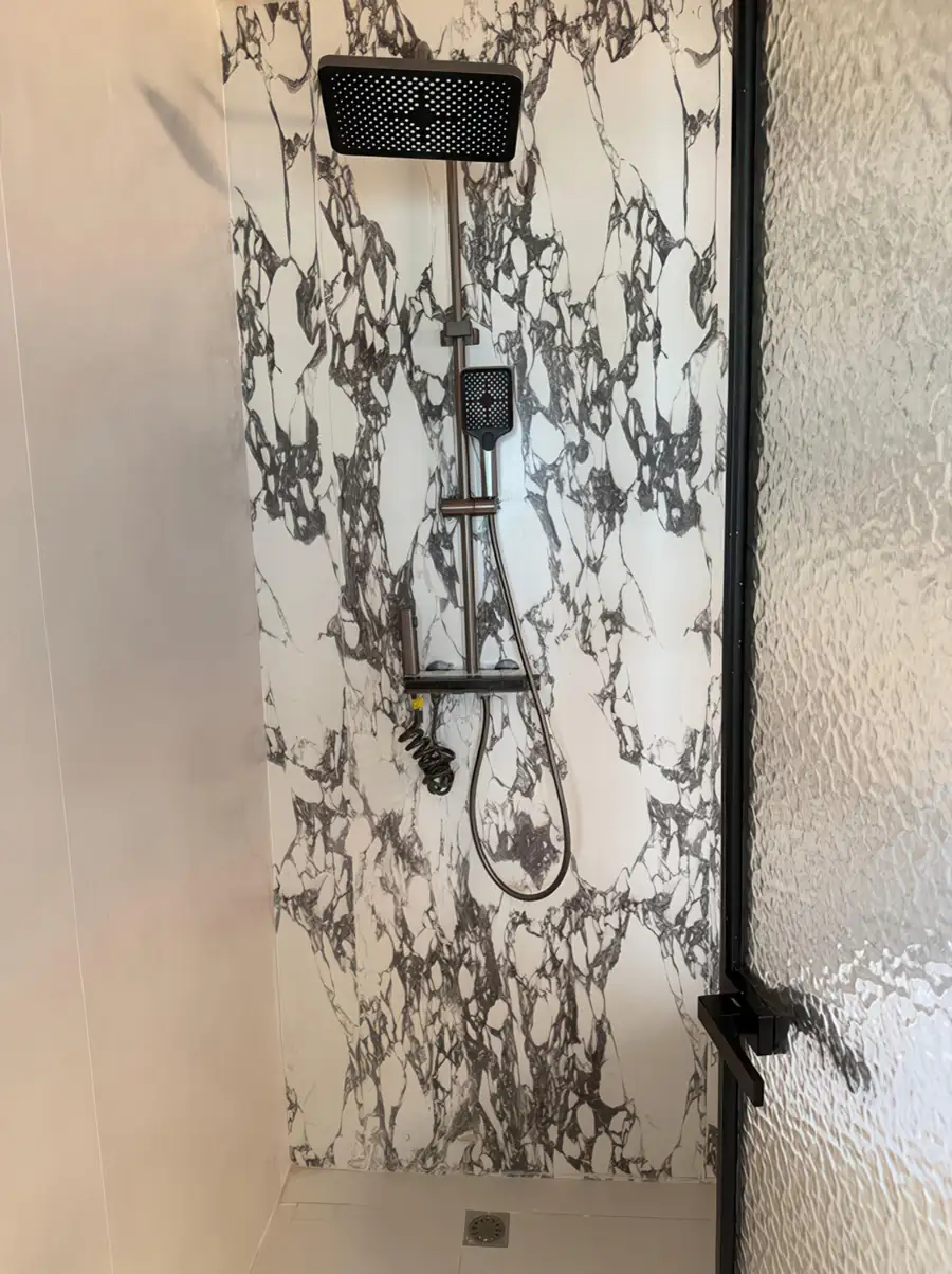 An open-concept bathroom at Jelly Sea Resort detailing a light wood vanity desk, an illuminated backlit mirror, a wall-mounted hair dryer, a white toilet, and a glass-partitioned electric shower.