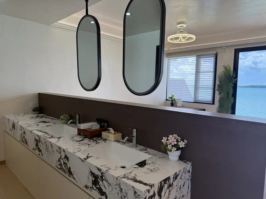 A detailed view of the bathroom at Jelly Sea Resort showing the high-quality electric shower head, sleek metal fixtures, and beautifully textured wall tiles.