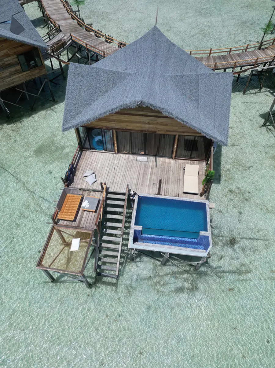 An overwater balcony featuring lounge chairs, a white mesh bed net, a private swimming pool, and direct access to the sea, constructed in a local style at Jelly Sea Resort.